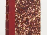 un vieux livre à la couverture rouge posé sur une surface blanche