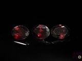 three pieces of red garnets sitting on top of a black surface