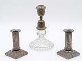 deux bougeoirs en argent et un bougeoir en verre sur fond blanc