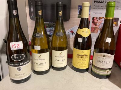 Plusieurs bouteilles de vin sont alignées sur le plan de travail d'une cuisine