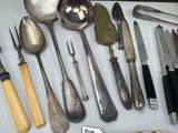 many different types of knives and spoons laid out on a table