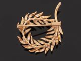 a close up of a gold brooch with leaves on a black background