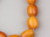 an orange beaded necklace with a silver clasp on a gray surface
