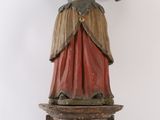 une vieille statue en bois représentant une femme debout sur une caisse