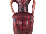 un vase rouge muni d'une anse sur fond blanc