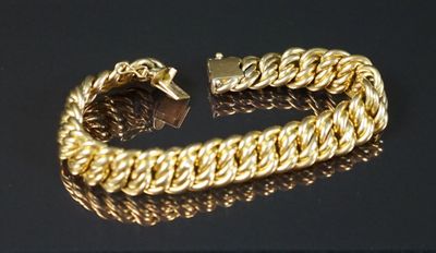 gros plan d'un bracelet en or sur une surface noire