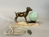 a statue of a goat on a marble base next to a light bulb
