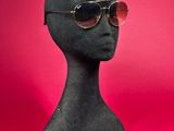 sunglasses on a mannequin head against a pink background