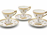 trois tasses et soucoupes sont posées sur une surface blanche