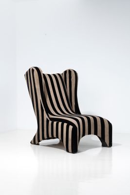 une chaise rayée dans une pièce blanche, avec une chaise rayée en noir et blanc