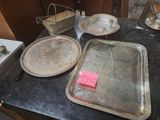 une table sur laquelle sont posés de nombreux plateaux en argent