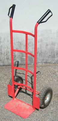 un diable rouge avec une poignée noire dans la rue