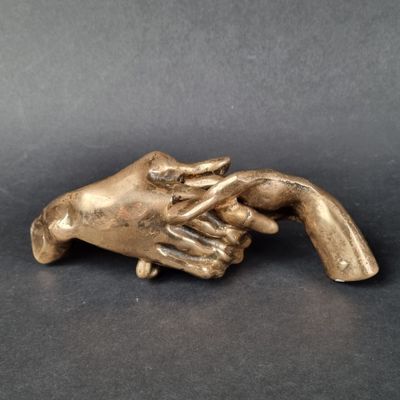 une image représentant une statue en bronze d'une main tenant une autre main