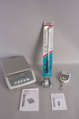 a electronic scale with a pen on it next to other electronic items