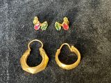 deux paires de boucles d'oreilles en or ornées de pierres colorées sur un fond noir