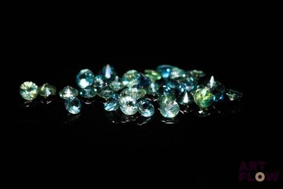 un tas de pierres précieuses bleues et vertes sur une surface noire