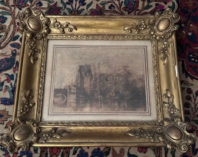 une vieille photo d'un château dans un cadre doré, posée sur un tapis