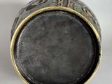 an old black and gold vase sitting on top of a white table