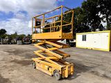 yellow scissor sitting on top of a wooden platform in a parking lot