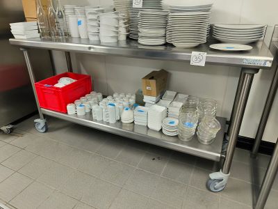 de nombreuses assiettes et tasses posées sur une étagère métallique dans une cuisine