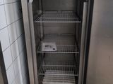 an empty refrigerator in the corner of a tiled room