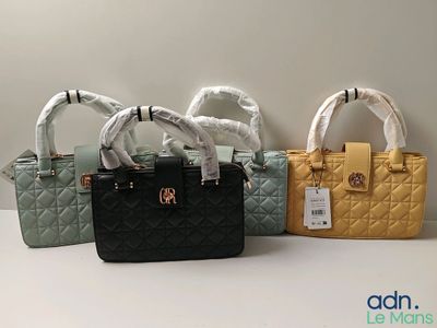 Trois sacs à main sont alignés sur une table, accompagnés d'une étiquette de prix