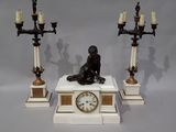 une statue représentant un homme assis sur un socle, avec une horloge