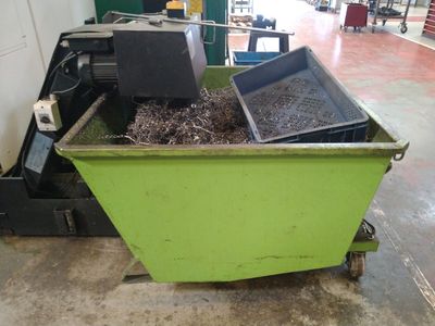 un bac vert rempli de terre à côté d'une machine