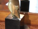 a bronze statue of a woman sitting on a marble block
