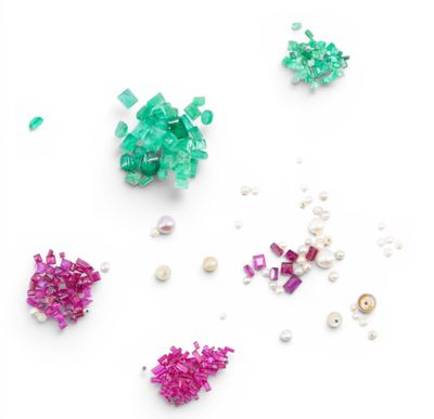 some green and pink beads and pearls on a white surface