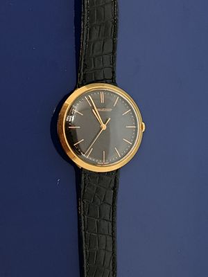 une montre-bracelet noire et dorée sur un fond bleu