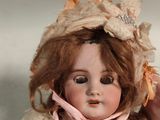 a close up of a doll with a pink dress and hat