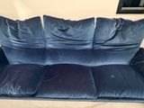 a blue velvet couch with three pillows on it