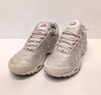 Les baskets Nike Air Max 95 blanches et rouges sont posées sur une surface blanche