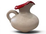a white vase with a red lid on a white surface