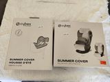 two boxes of baby car seat covers on a bed with a white blanket