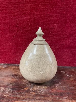 un vase blanc posé sur une table, avec un mur rouge en arrière-plan