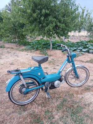 un cyclomoteur bleu garé dans l'herbe
