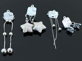 three pairs of silver earrings and a pair of silver earrings on a black surface