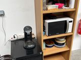 a microwave and a cabinet in the corner of a room