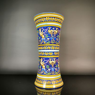 un vase bleu et jaune posé sur une table noire