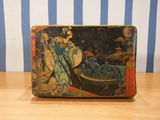 a small metal box with a painting on it