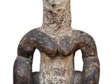 une vieille statue représentant un homme assis sur une chaise, les mains posées sur les genoux