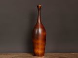 un vase marron posé sur une table en bois devant un mur gris