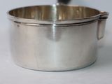 a silver pot with a spoon in it on a white surface