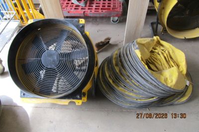 deux tuyaux jaunes et un ventilateur noir posés par terre