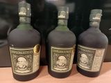 trois bouteilles de rhum posées sur un comptoir, à côté d'un sac noir