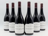 six bouteilles de vin sont alignées sur une surface blanche
