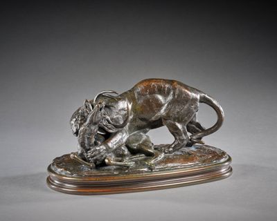 statue en bronze représentant un lion attaquant un sanglier, posée sur un socle en bois