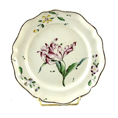 une assiette sur laquelle est peinte une fleur, posée sur un socle